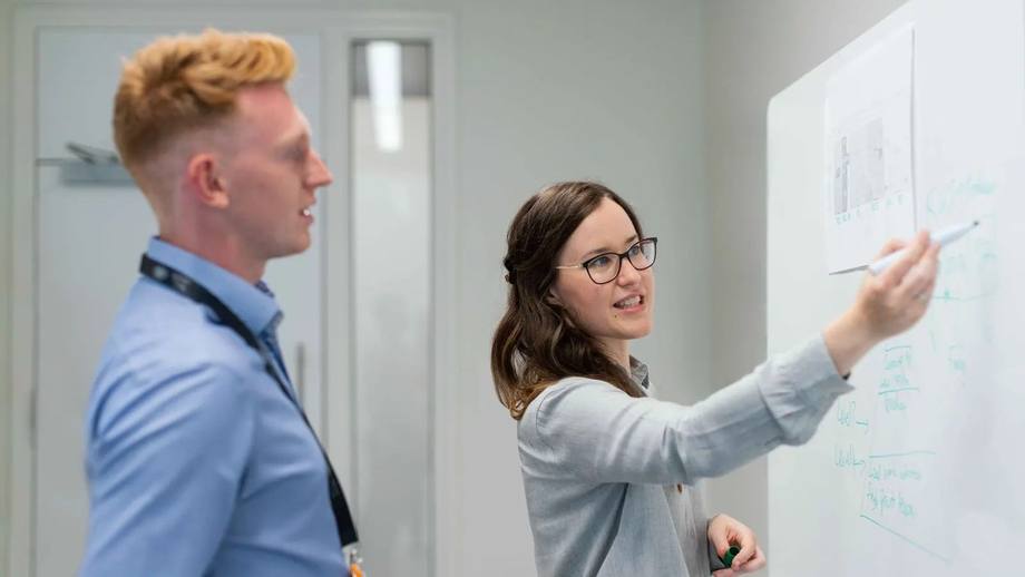 Two colleagues planning a project at a whiteboard